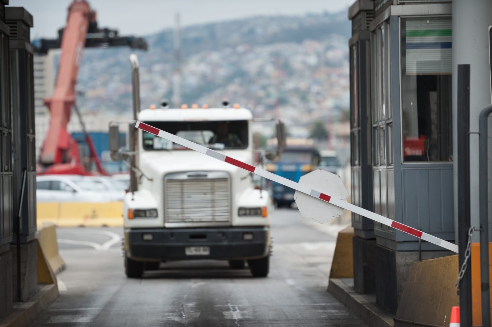 A semi-truck crosses through a border checkpoint for international freight delivery between North American countries, representing cross-border shipping.