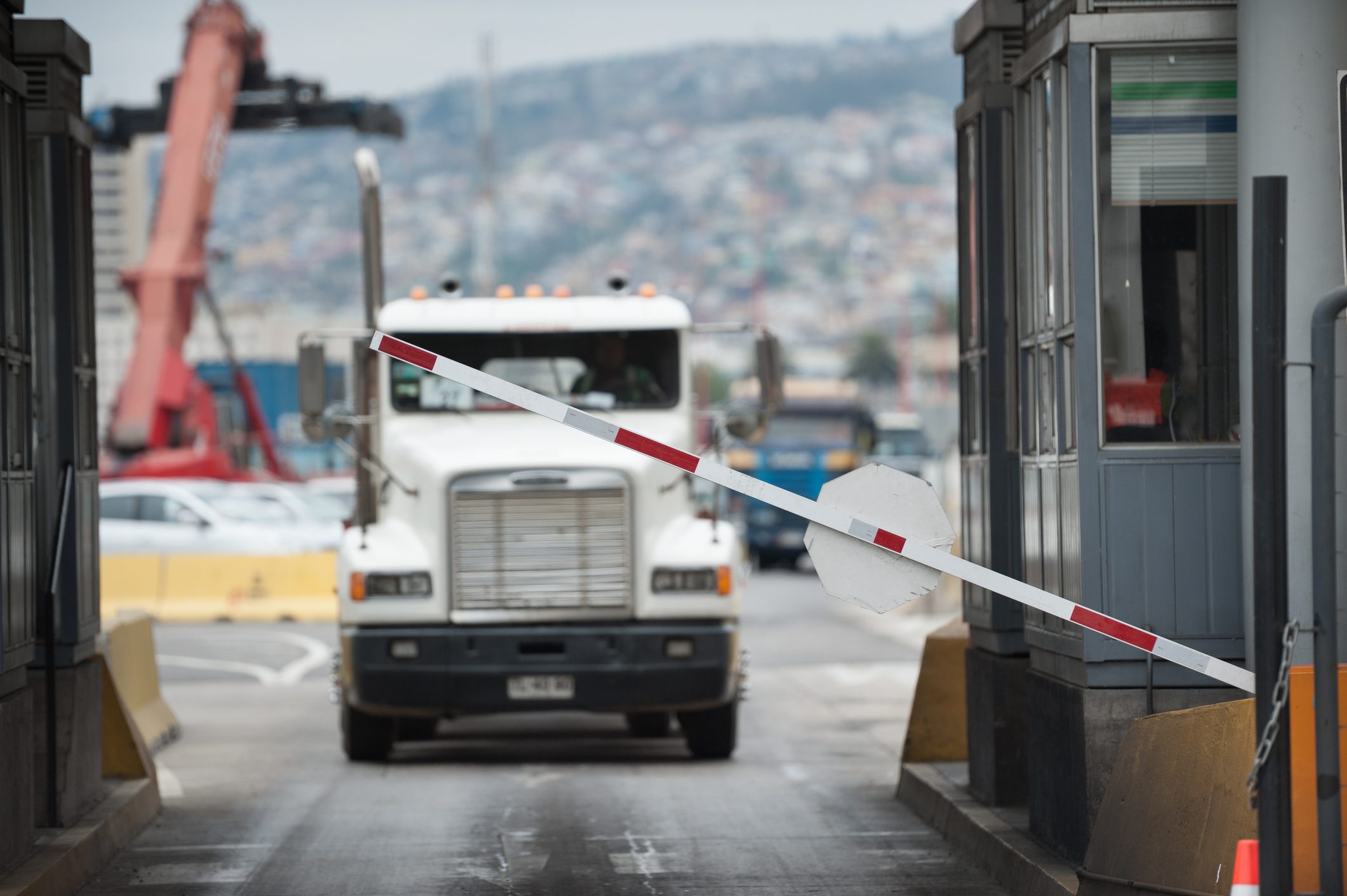 A semi-truck crosses through a border checkpoint for international freight delivery between North American countries, representing cross-border shipping.