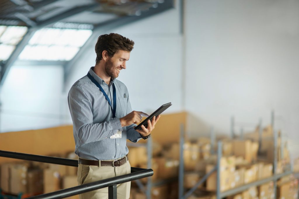 Logistics manager using a tablet in a warehouse to track shipments, symbolizing real-time freight monitoring and operational control